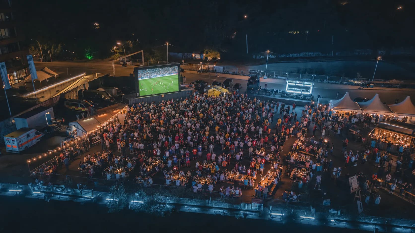 Nachtluftbild vom Public Viewing Hamburg mit voller Fläche, beleuchteten Tischen und Fußball-Leinwand